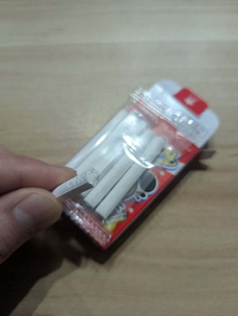 Holding one Cola Cigarette ramune candy stick taken from the box
